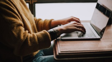 Profile shot of a person typing on a laptop.