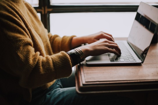 Profile shot of a person typing on a laptop.