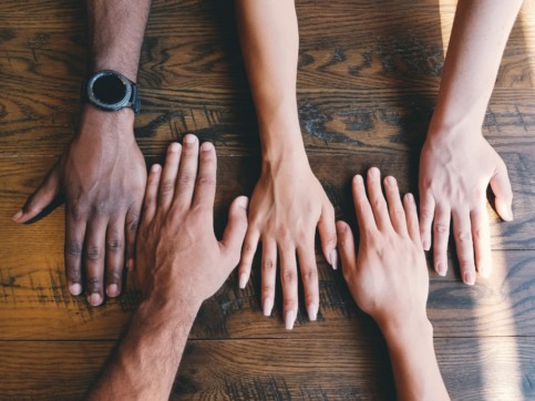 A group of hands laid out on a table together.