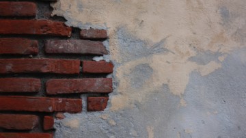 Brick wall half-covered in plaster.