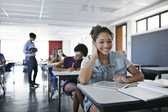 Female student smiling to camera in classroom.