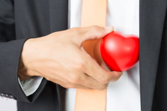 Businessman holds out the red heart, isolated background