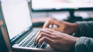 Closeup of hands typing on a laptop.