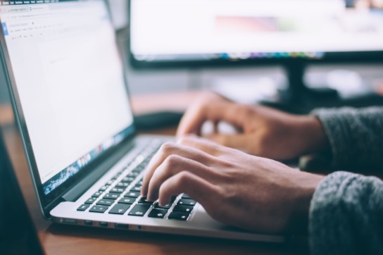 Closeup of hands typing on a laptop.