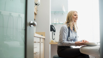 Female doctor with medical record sitting examination room