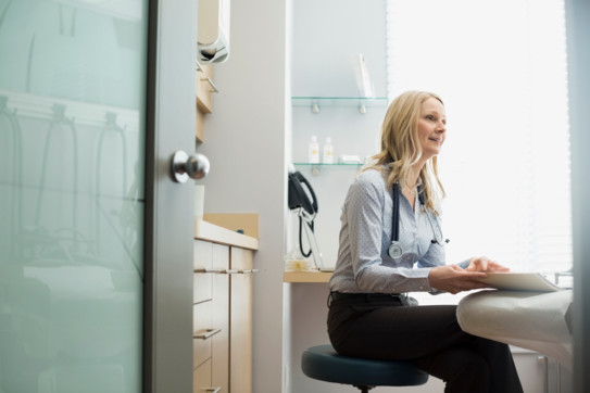 Female doctor with medical record sitting examination room