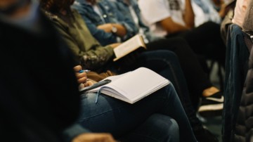 Closeup of an audience member taking notes.